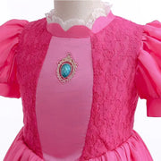 Close-up of the pink layered dress for girls featuring lace and a decorative jewel, ideal for summer and special occasions.